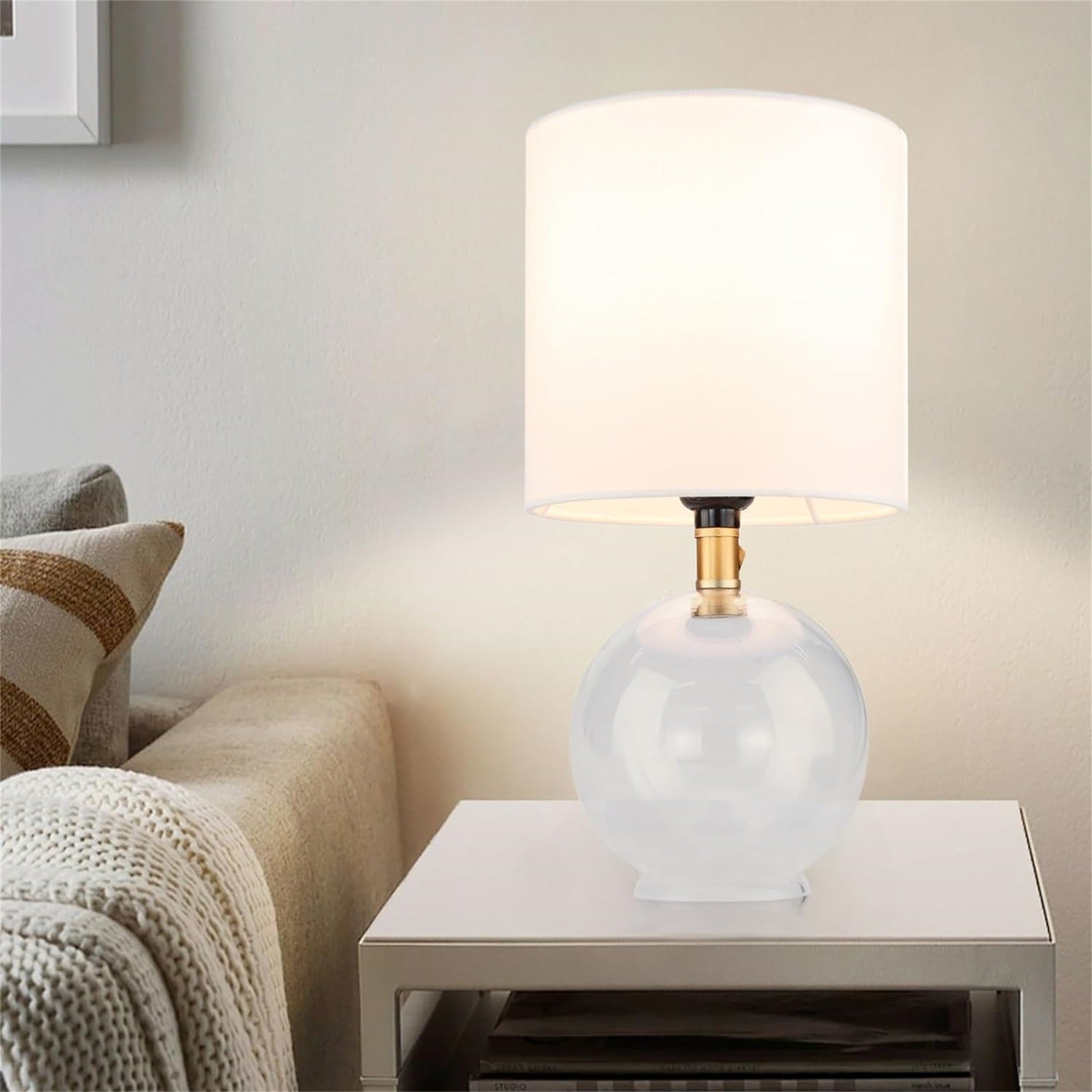 Table lamp with a white shade on a side table in a living room setting.
